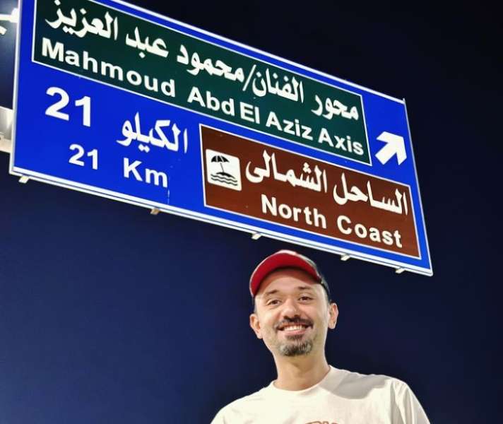 كريم محمود عبد العزيز يلتقط صورة مع لافتة محور يحمل اسم والده